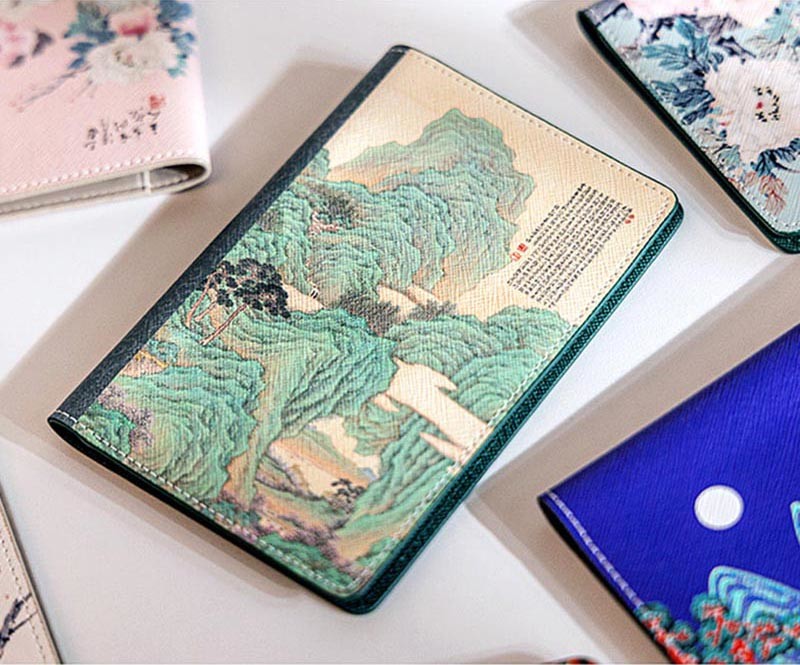 [텍스트: 판독 불가 한자문] 합성가죽 재질에 전통 산수화 ‘도원행주도’ 문양을 인쇄한 여권지갑, 연두와 베이지 색조의 조화가 돋보이는 디자인