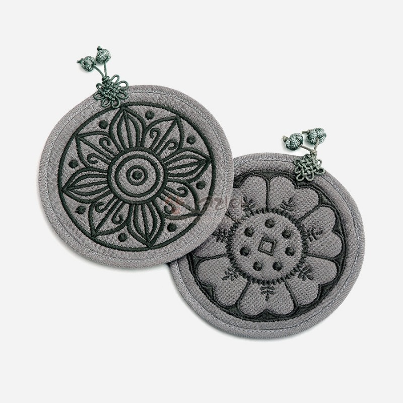 회색 천 재질에 고구려·백제 수막새 연꽃 문양 자수 장식, 매듭 노리개 포인트가 더해진 원형 컵받침 2P 세트.