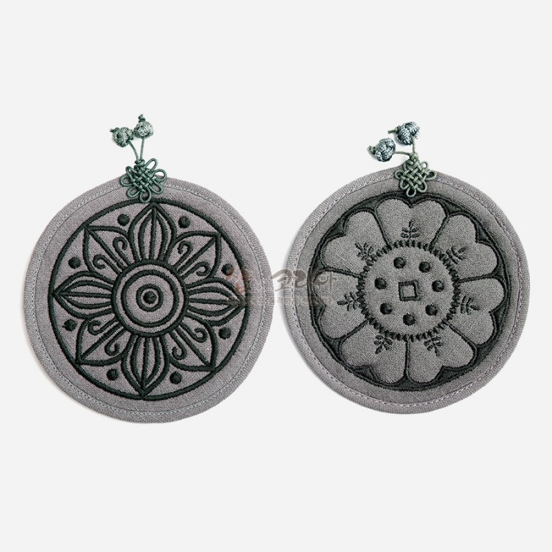 회색 천 소재에 고구려·백제 수막새 문양을 자수로 표현하고 매듭 장식을 더한 원형 컵받침 2P 세트.