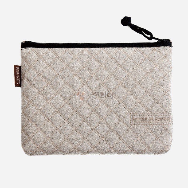 베이지 린넨 소재에 다이아몬드 퀼팅 누비 기법을 더한 직사각형 지퍼 파우치.