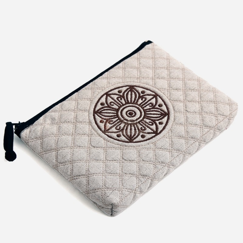 연한 회색 누빔 원단 위에 갈색 고구려 수막새 문양 자수와 검은 지퍼 장식이 조화로운 파우치.