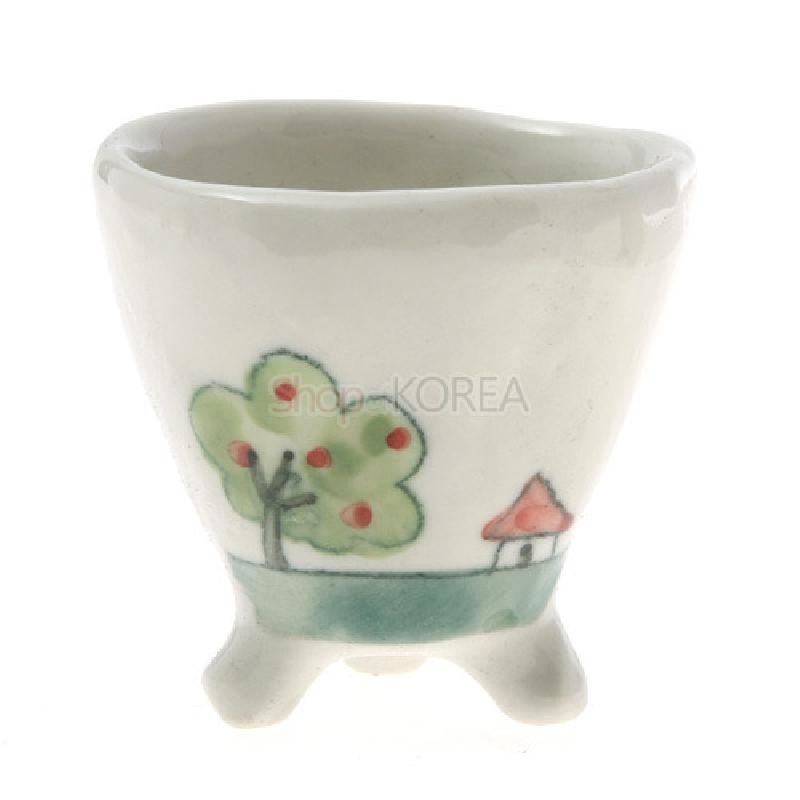 백색 도자기 재질에 삼각형 다리 구조, 손그림 기법의 나무와 작은 집 풍경 문양이 그려진 소주잔.