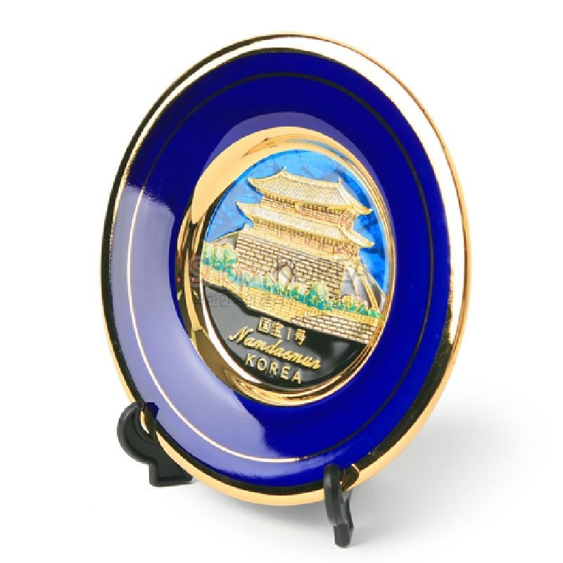 청색 바탕과 금장 테두리에 남대문 입체 부조가 표현된 금속 재질 장식 접시.