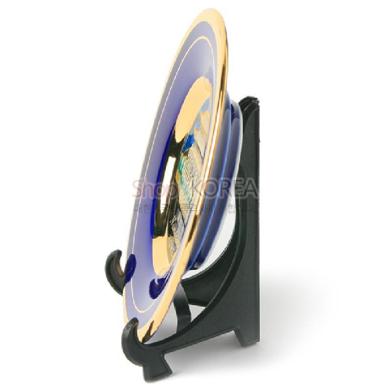 청색 바탕 위 금장 테두리가 둘러진 금속 접시 형태의 남대문 장식, 검은 받침대 구성.