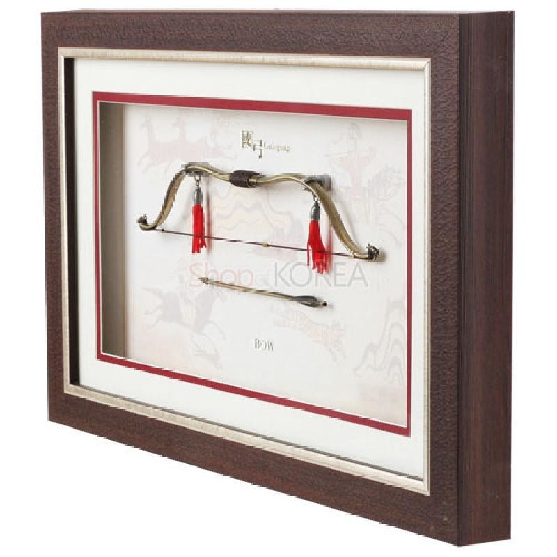 짙은 갈색 나무 액자에 금속 재질 국궁과 화살을 입체 배치하고 붉은 술 장식과 전통 기마도 배경이 어우러진 인테리어 장식.