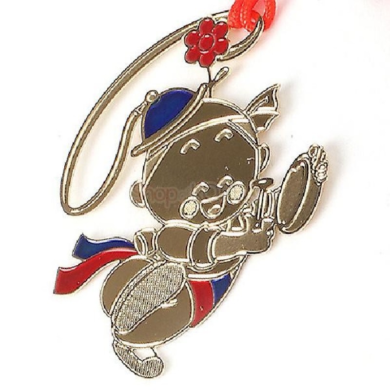 금속 재질에 금장 마감된 농악 소년 형상, 붉은색과 파란색 에나멜 채색과 꽃 장식 매듭끈이 어우러진 책갈피.