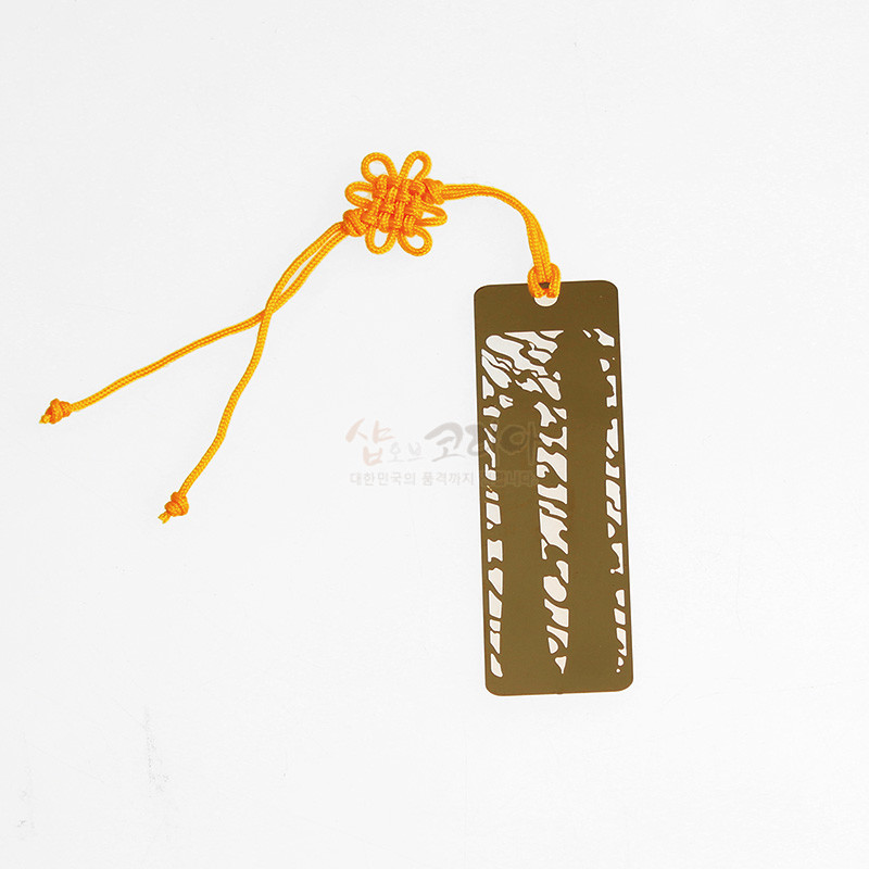 금속 재질에 장승 형상을 레이저 컷팅한 직사각형 책갈피와 노란 전통 매듭끈 장식.