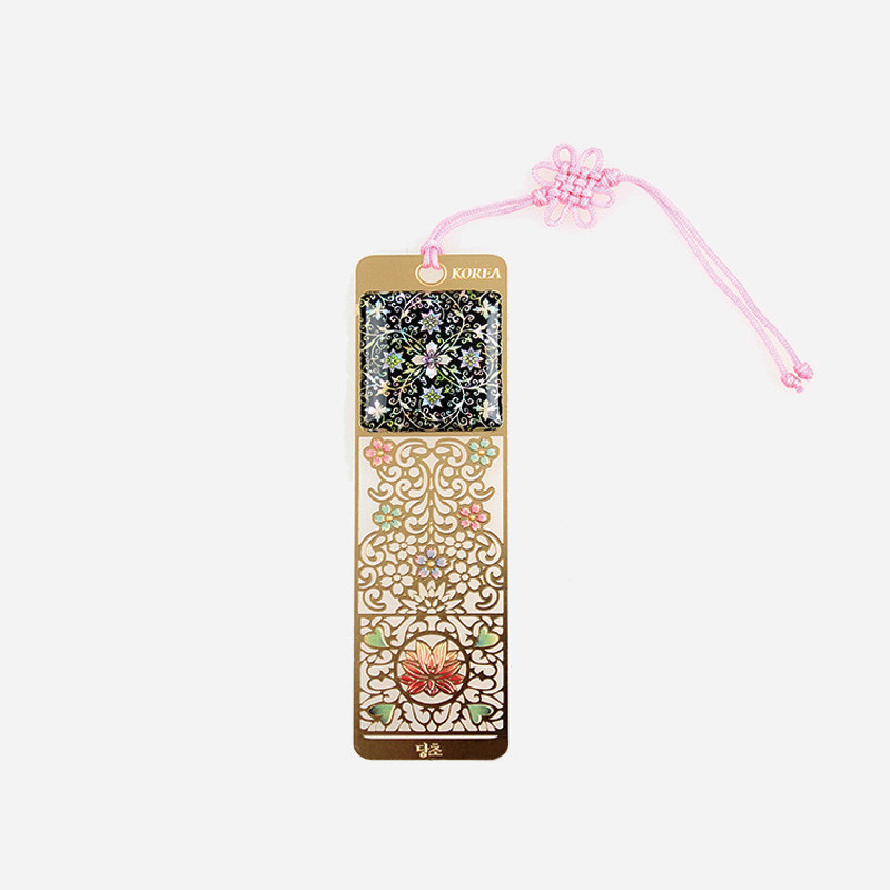 금속 소재 바탕에 자개 상감과 다채로운 당초무늬, 꽃문양이 장식된 책갈피, 분홍 매듭 끈 장식.
