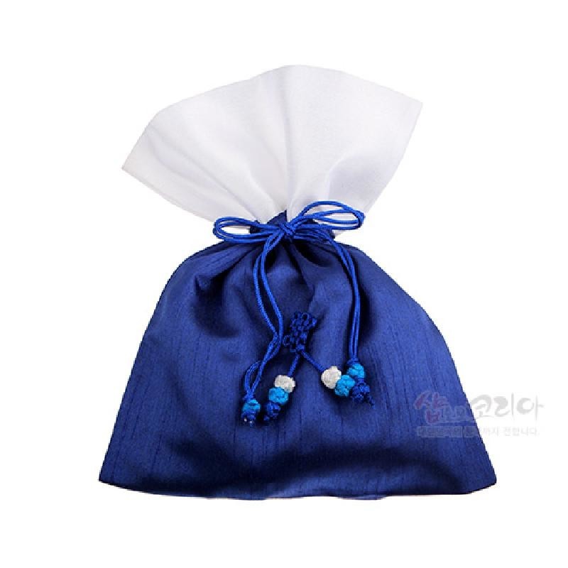 남색 몸판과 흰색 상단이 대비되는 전통 매듭주머니로, 광택 있는 원단과 파란 끈·매듭 장식, 구슬 장식을 사용한 심플한 디자인