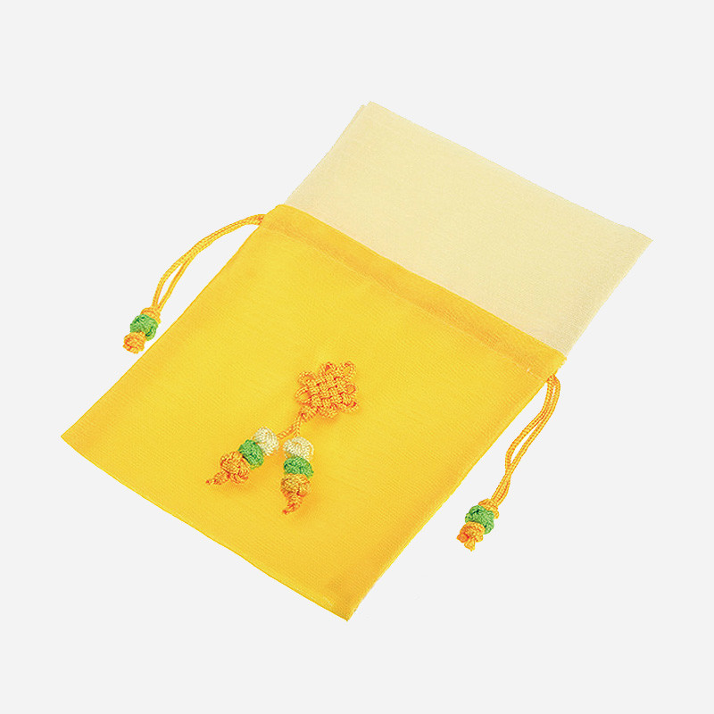 노랑과 연아이보리 비단으로 만든 주머니에 전통 매듭 장식과 녹색·주황색 매듭끈 포인트가 있는 디자인