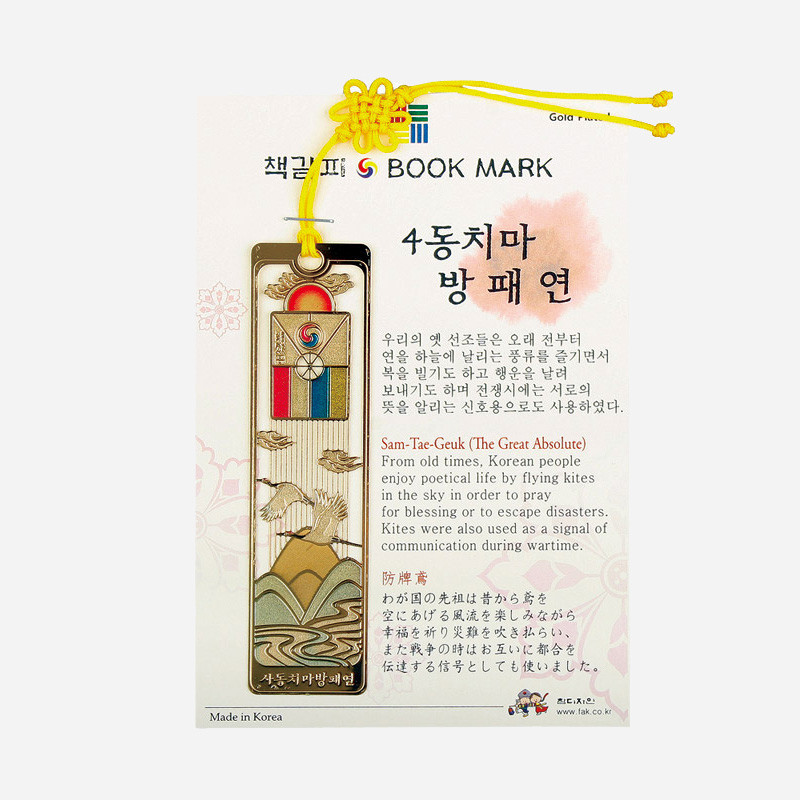 금속 재질에 삼태극과 4동치마 방패연, 산수와 학 문양을 금장으로 새긴 책갈피, 노란 매듭 끈 장식.