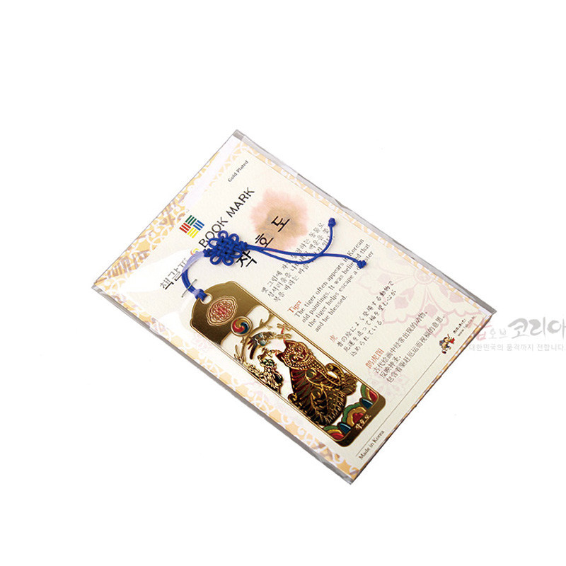 금속 재질에 금장 처리된 직사각형 책갈피, 호랑이와 까치 문양과 태극 장식, 청색 전통 매듭끈 장식.