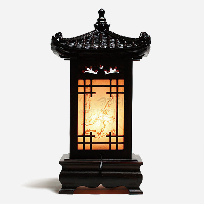짙은 목재 기와 지붕과 받침 위에 창살 무늬와 한지 풍 산수화, 상단 학 문양이 어우러진 전통 좌등.