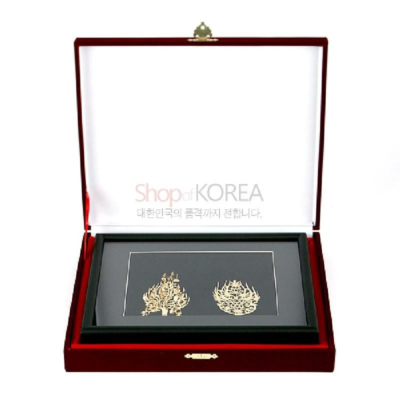 검은 바탕 액자 속에 금속 재질로 정교하게 투각된 왕과 왕비 금제관식 문양을 담은 장식품.