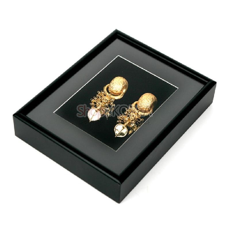 검은색 액자 속 금빛 금속 태환이식 장식을 배치한 액자형 공예품, 입체적인 장식 구조와 대비되는 단색 배경이 특징인 장식품.