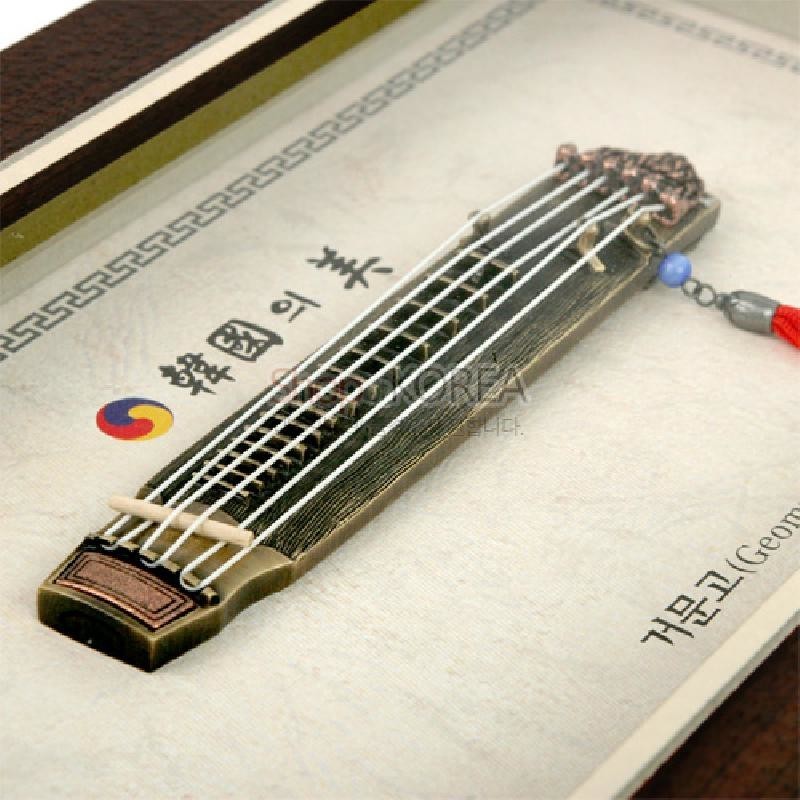 나무 재질의 미니 거문고 입체 장식과 오방색 매듭 장식이 포함된 액자형 전통 악기 장식품. 나무 재질의 미니 거문고 입체 장식과 오방색 매듭 장식이 포함된 액자형 전통 악기 장식품.