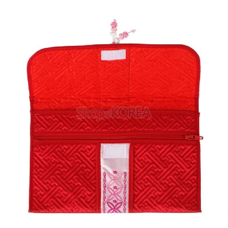 선명한 적색 누비 천으로 제작된 지갑으로, 전면에 전통 기하학 무늬와 분홍·흰색 자수띠 장식이 있는 디자인