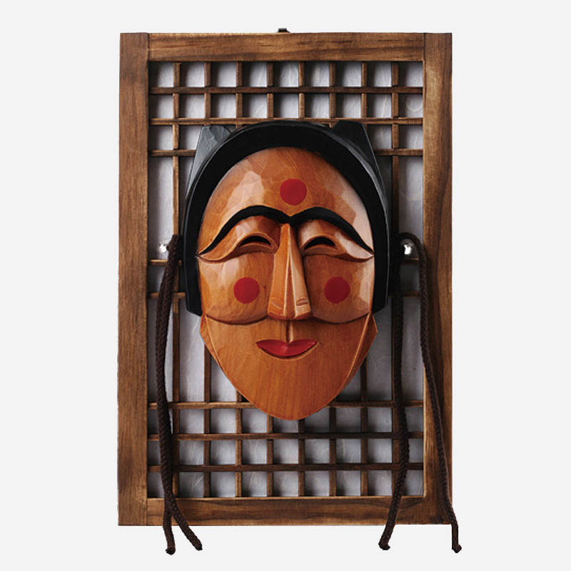 목재 문창살 액자에 걸린 전통 부네탈 조각 장식, 붉은 원형 문양과 자연 목재 색감이 조화된 인테리어 소품.