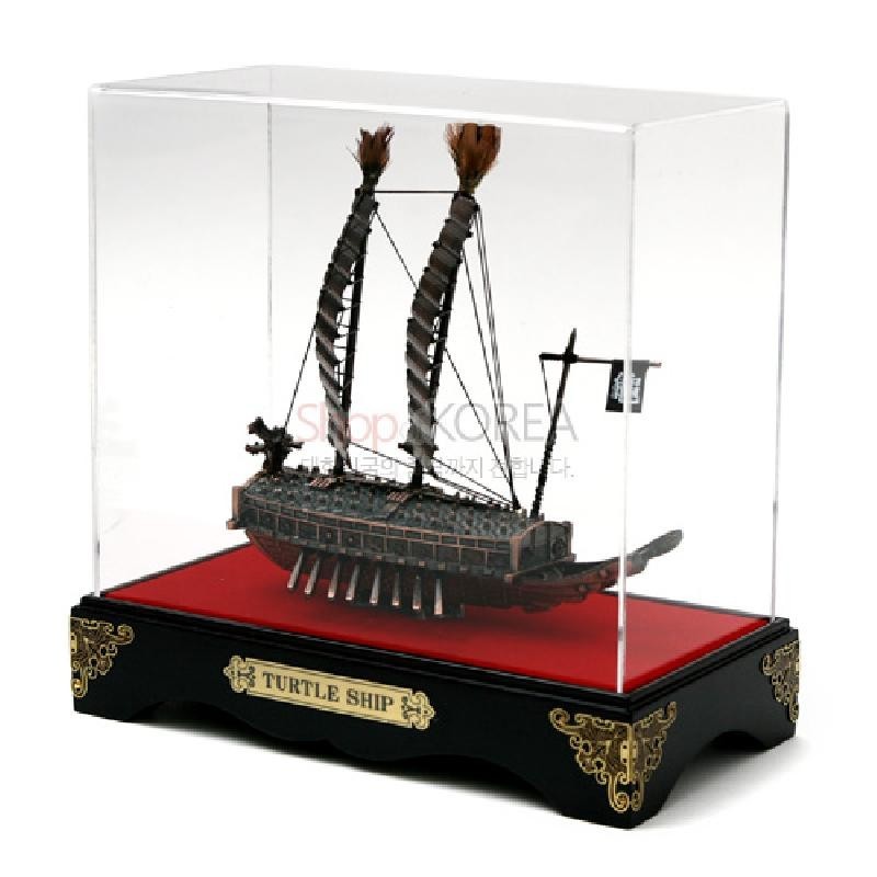 금속 재질로 정교하게 표현된 거북선 모형과 붉은 바닥, 금색 장식이 들어간 흑색 받침대, 투명 아크릴 케이스 구조의 장식품.