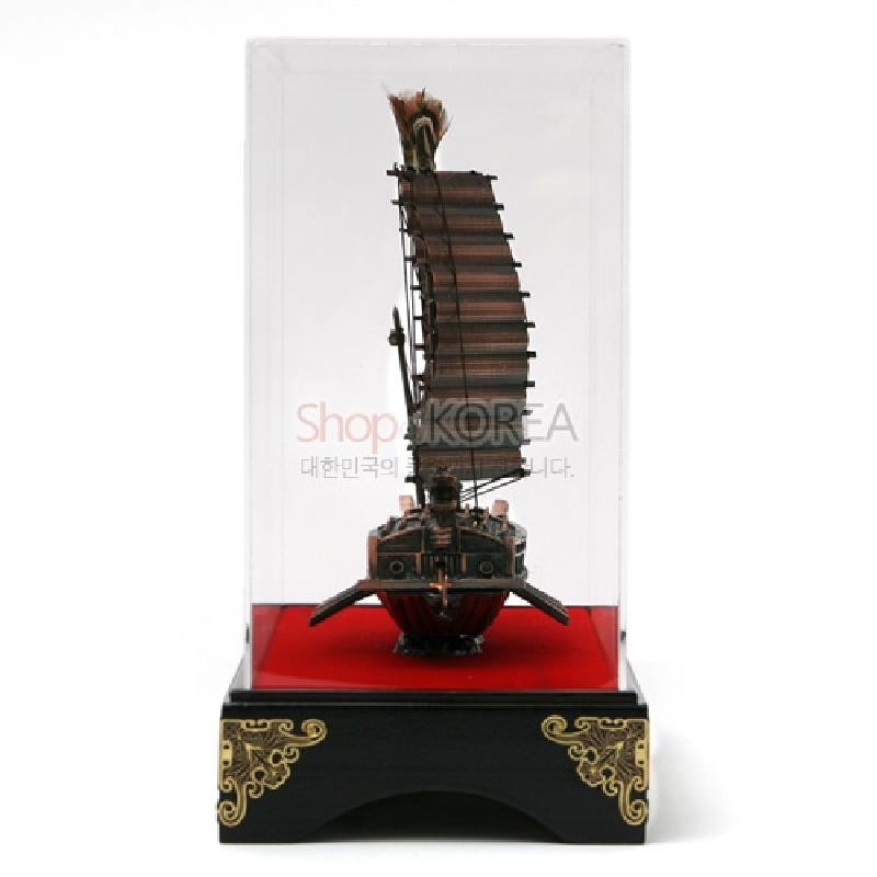나무 재질로 세밀하게 조각된 동거북선 모형과 붉은 바닥, 금색 문양 장식 흑색 받침대가 특징인 장식품.