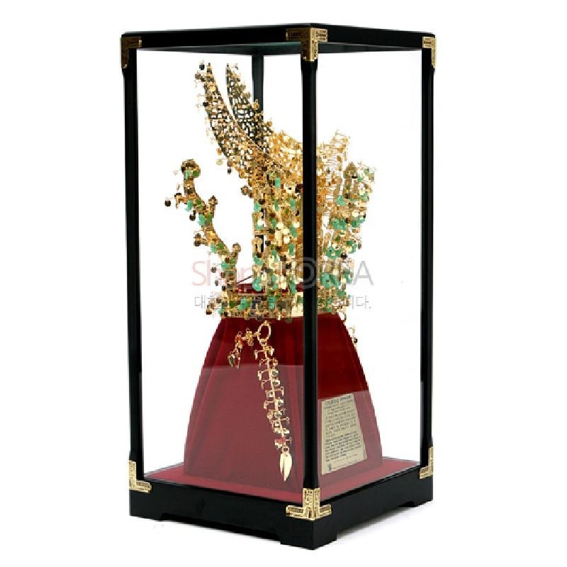 금속 재질로 제작된 금관 미니어처와 녹색 장식, 붉은 비단 받침 및 유리 보호 케이스 구성이 특징인 장식품.