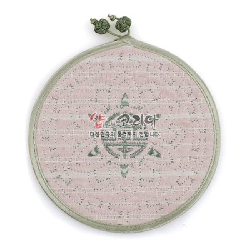 연한 분홍색 천에 초록색 실로 연꽃문양을 누비 기법으로 수놓은 원형 컵받침, 가장자리 배색과 매듭 고리가 포인트인 구성.