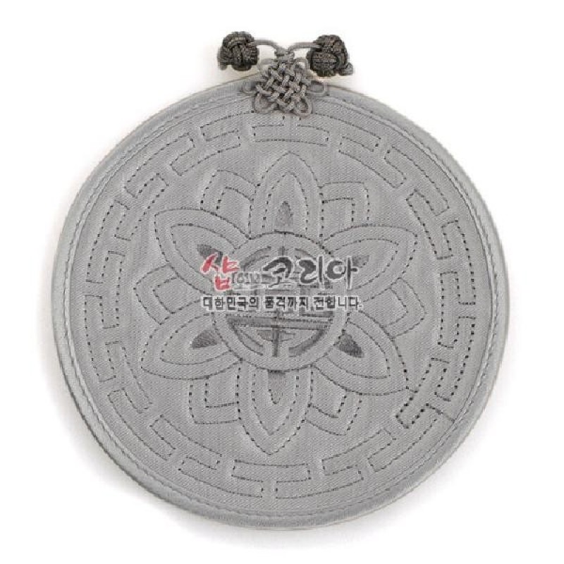 은은한 회색 천 소재에 누비 기법으로 연꽃문과 전통 기하학 문양을 넣은 원형 컵받침, 윗부분 매듭 장식 포인트.