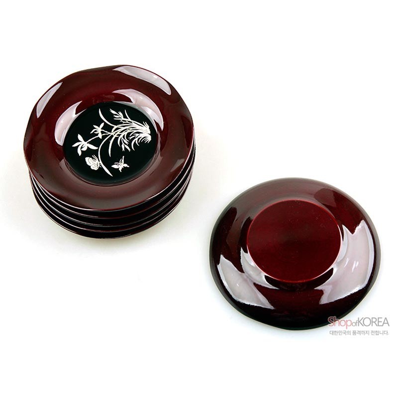 진한 와인빛 옻칠 바탕에 중앙 흑색 면과 흰색 난초 문양이 대비되는 원형 나전칠기 컵받침 4종 세트.