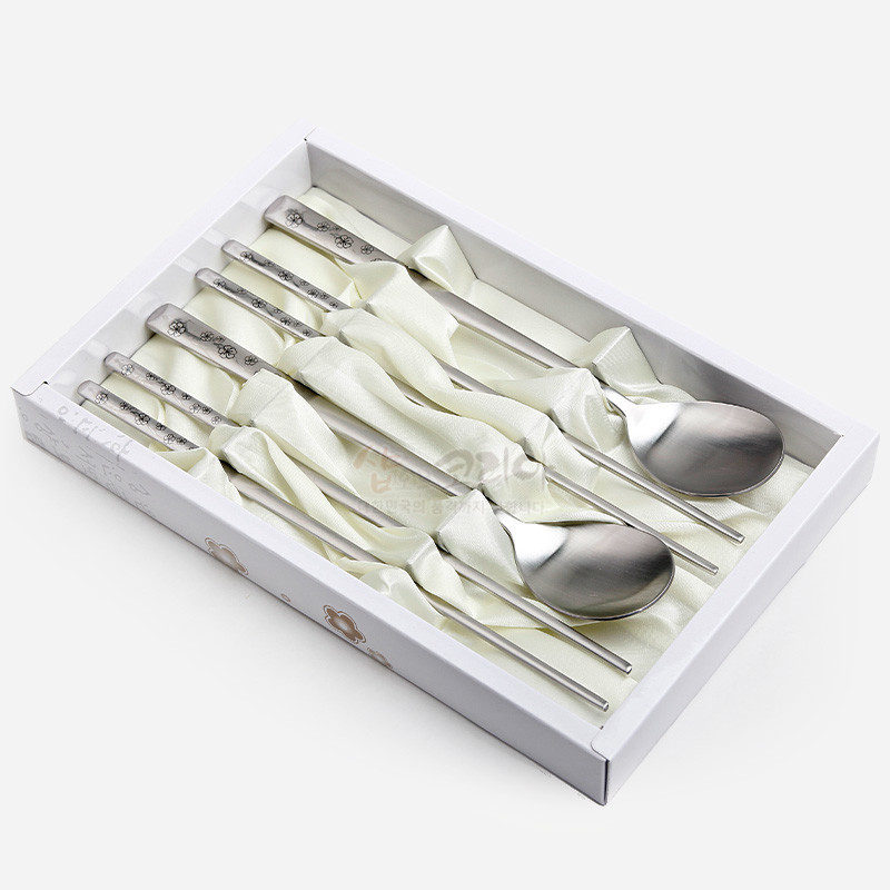 스테인리스 재질에 손잡이 부분 매화 문양이 음각된 은색 전통 수저 2인조 세트.