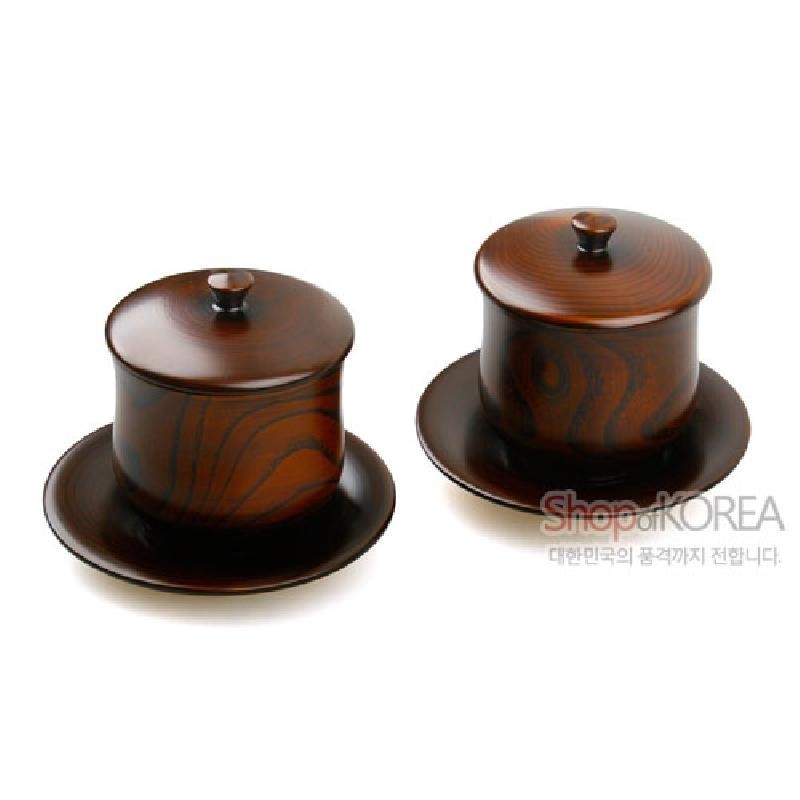 나뭇결 무늬가 드러난 목재 위에 갈색 계열 천연 옻칠을 입힌 뚜껑과 받침 포함 찻잔 세트.