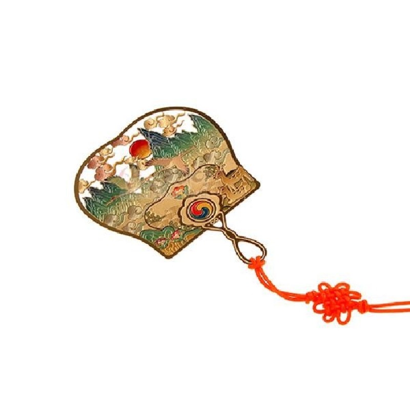 금속 소재에 금장 처리된 부채 모양 책갈피, 십장생 산수문과 태극 문양, 주황색 전통 매듭 장식이 있는 디자인.