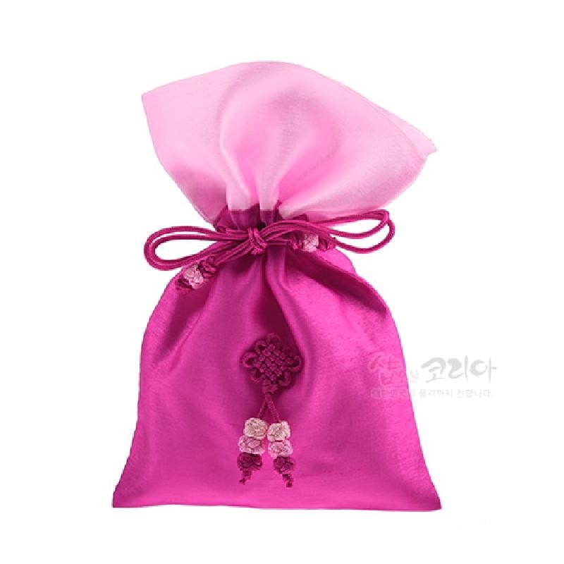 진분홍색 실크 재질의 전통 매듭주머니로, 옅은 분홍 상단과 조화로운 명주 끈, 정교한 매듭 장식이 특징인 공예품이다.