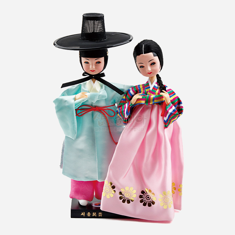 비단 재질로 제작된 선비와 여인 한복 인형 세트, 연분홍 치마와 꽃문양, 오방색 줄무늬 저고리와 갓 장식이 특징인 상품.