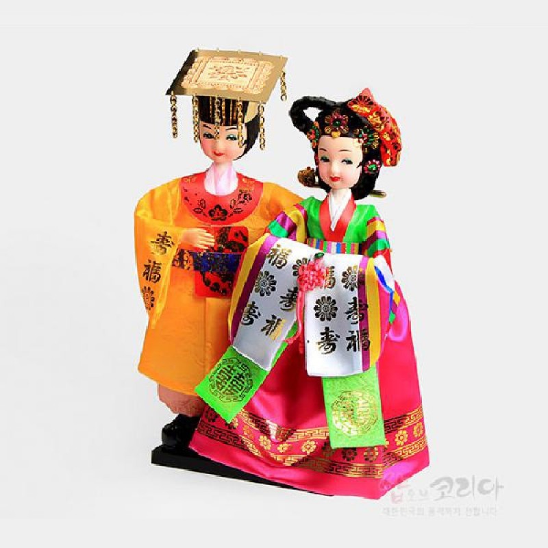 화려한 비단 재질로 제작된 왕과 비 전통 한복 인형, 금속 장식 관과 오색 단청 무늬, 수복 문자와 꽃문양 수놓인 쾌자와 치마가 특징인 장식 인형. 화려한 비단 재질로 제작된 왕과 비 전통 한복 인형, 금속 장식 관과 오색 단청 무늬, 수복 문자와 꽃문양 수놓인 쾌자와 치마가 특징인 장식 인형.