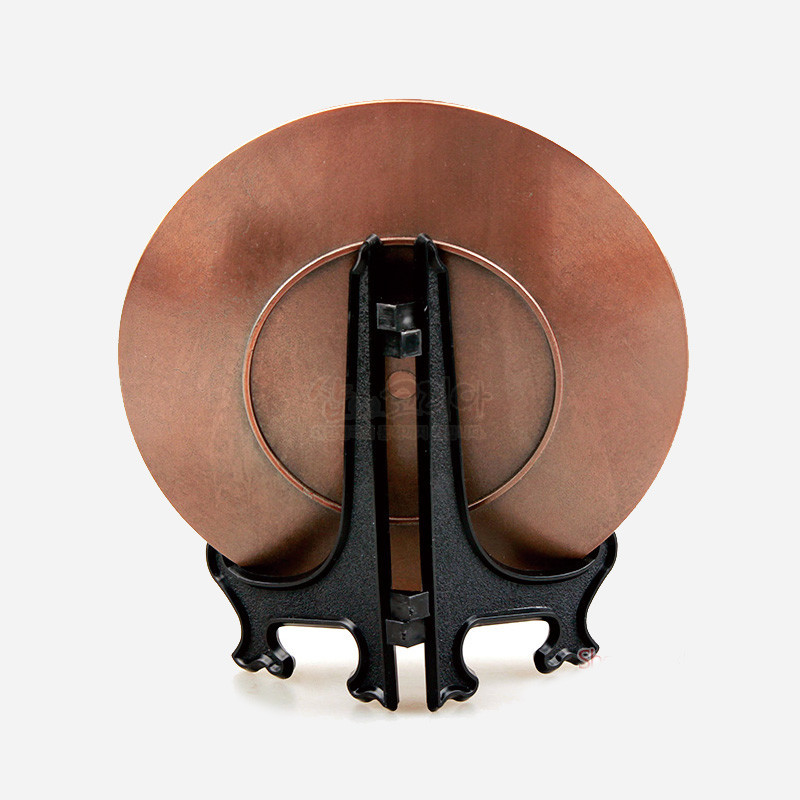 주석 재질의 원형 장식을 검은색 플라스틱 소재 받침대에 세운 구조의 장식 판.