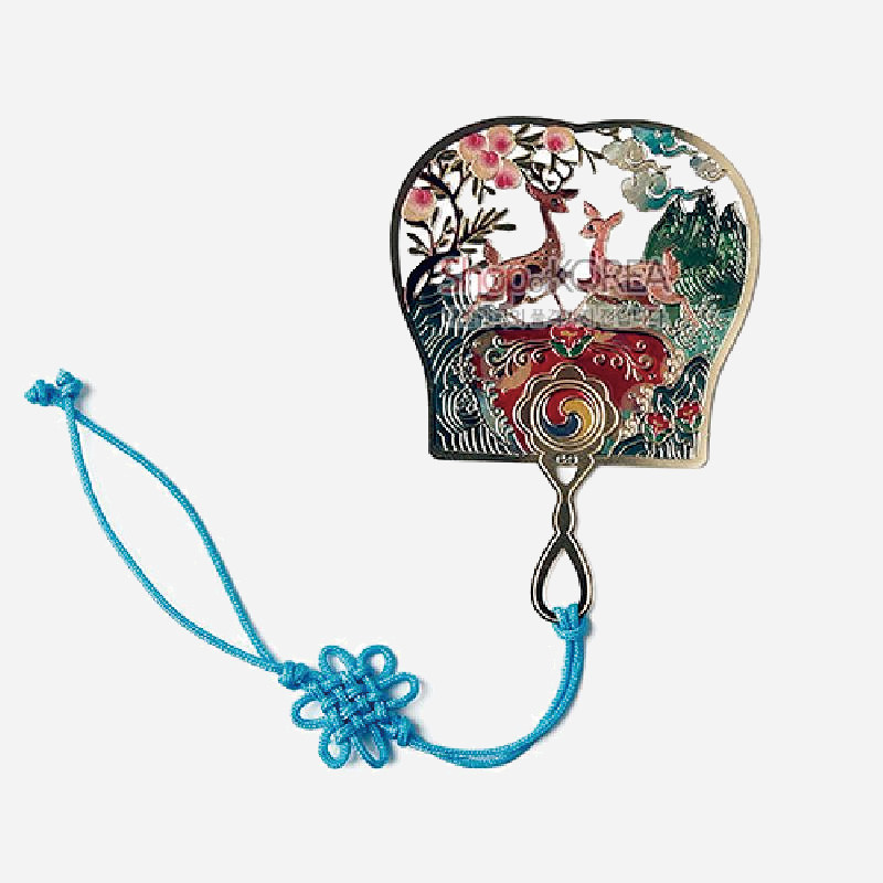 금속 소재에 칼라 에나멜 기법으로 사슴과 산수, 오색 태극 문양을 장식하고 청색 전통 매듭 끈을 더한 부채형 책갈피.