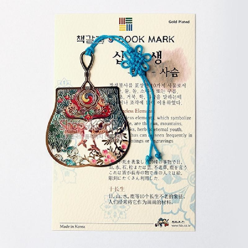 금장 처리된 금속 재질에 사슴과 꽃, 소나무 문양을 채색한 부채 모양 책갈피와 청색 전통 매듭 장식.