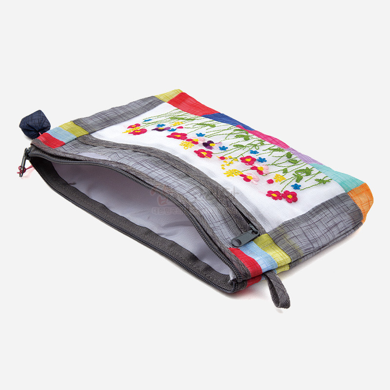 모시 소재에 다채로운 색상의 배색 천과 들꽃 자수 문양이 어우러진 지퍼형 파우치.