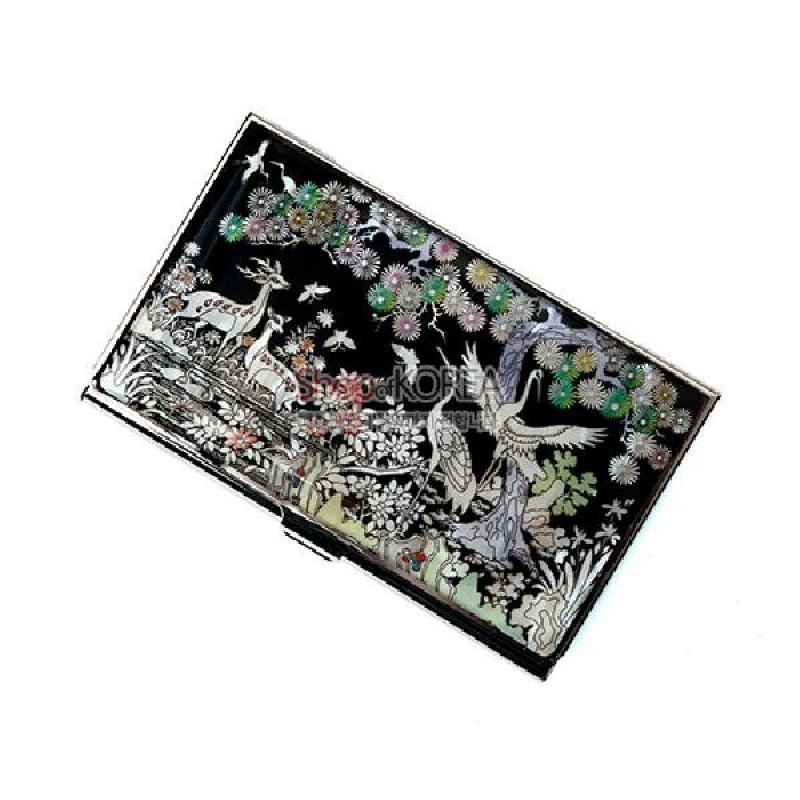 흑색 바탕 위에 자개 상감 기법으로 학과 사슴, 소나무, 국화가 섬세하게 표현된 장생도 문양의 금속 명함집.