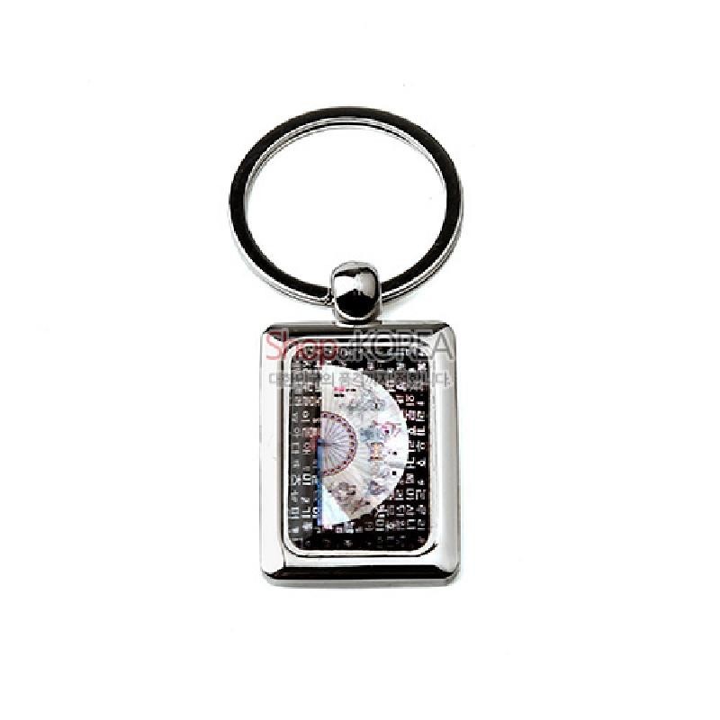 금속 사각 프레임 안에 자개 상감 부채와 검은 바탕의 훈민정음 글자 무늬가 어우러진 열쇠고리.