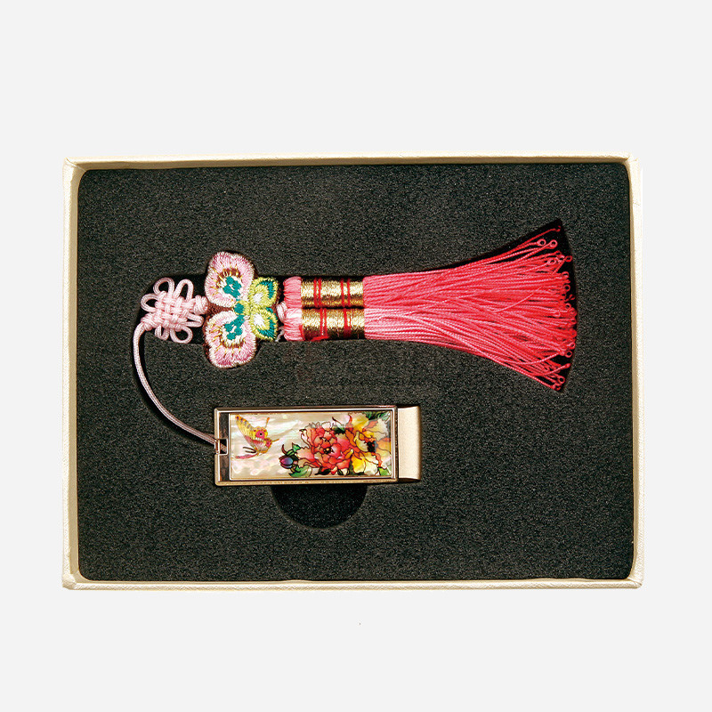 자개 상감으로 목단꽃과 나비 문양을 넣은 금속 USB 본체와 분홍색 나비 매듭, 술 장식이 조화를 이룬 전통 매듭 USB 장식.