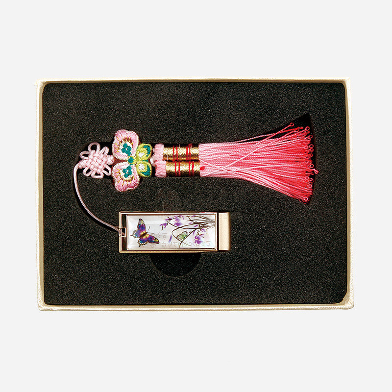 분홍색 전통 매듭과 술 장식이 연결된 금속 USB, 자개 상감 난초와 나비 문양이 돋보이는 디자인. 분홍색 전통 매듭과 술 장식이 연결된 금속 USB, 자개 상감 난초와 나비 문양이 돋보이는 디자인.