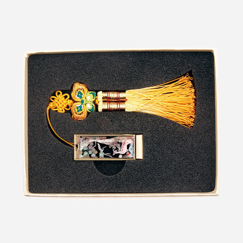 흑색 옻칠 바탕에 자개 상감 장생도 문양이 장식된 금속 USB와 황금색 술 매듭 비단 장식 세트.