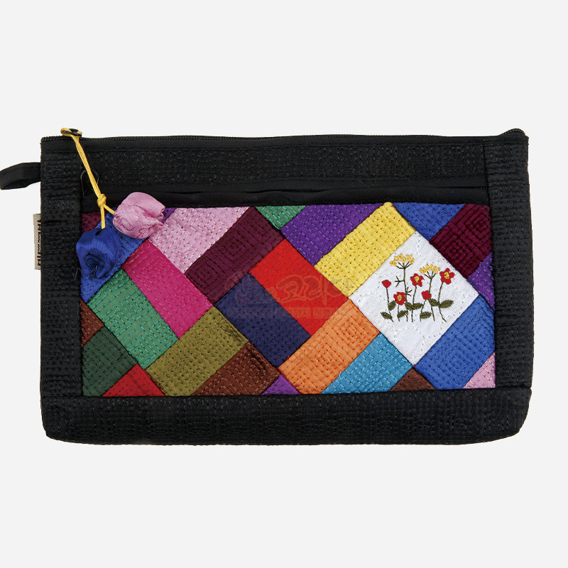 흑색 바탕에 다채로운 색상의 누비 조각보 패치워크가 어우러진 패브릭 파우치, 꽃 자수와 매듭 장식이 포인트인 디자인.