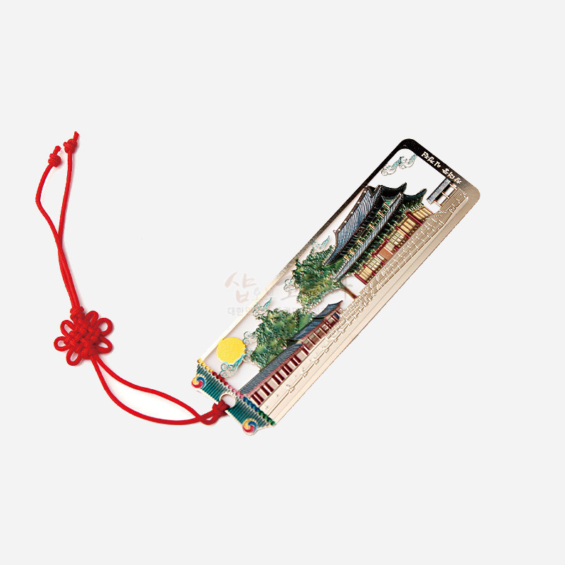 금속 재질 위에 창덕궁 인정전 전경을 섬세한 채색으로 표현하고, 붉은 전통 매듭끈 장식을 더한 책갈피. 금속 재질 위에 창덕궁 인정전 전경을 섬세한 채색으로 표현하고, 붉은 전통 매듭끈 장식을 더한 책갈피.