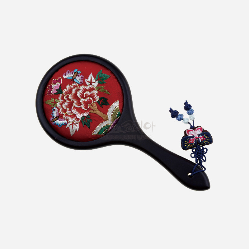 적색 비단 바탕에 모란과 나비 자수 문양이 놓인 손거울, 손잡이에 매듭 기법 술 장식이 더해진 디자인.