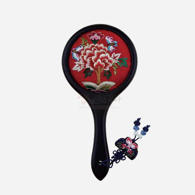 적색 비단 바탕에 모란과 나비 자수를 놓은 원형 손거울, 매듭 장식 술이 달린 디자인.