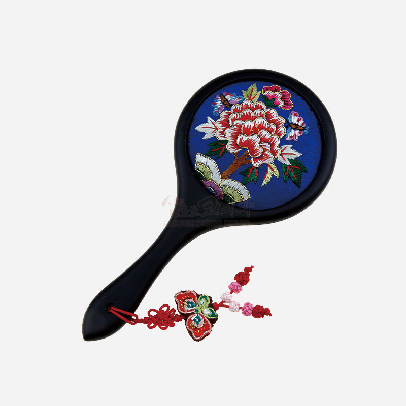 청색 바탕에 화려한 자수 모란과 나비 문양이 놓인 손거울, 매듭 장식이 달린 디자인.