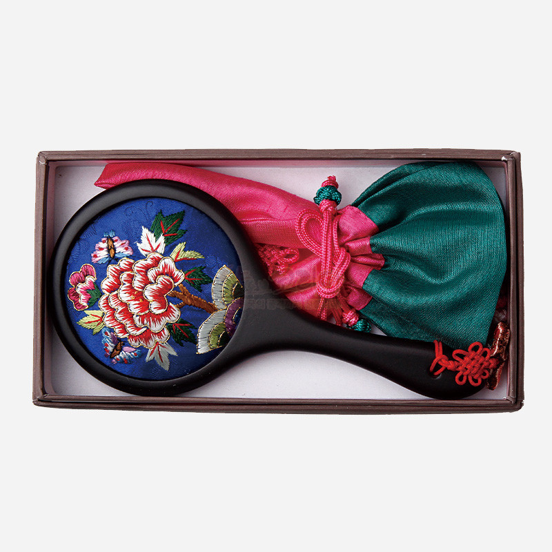 청색 비단 바탕에 화려한 모란과 나비 자수 문양이 놓인 손거울과 분홍·초록 색상의 비단 매듭 주머니 구성.