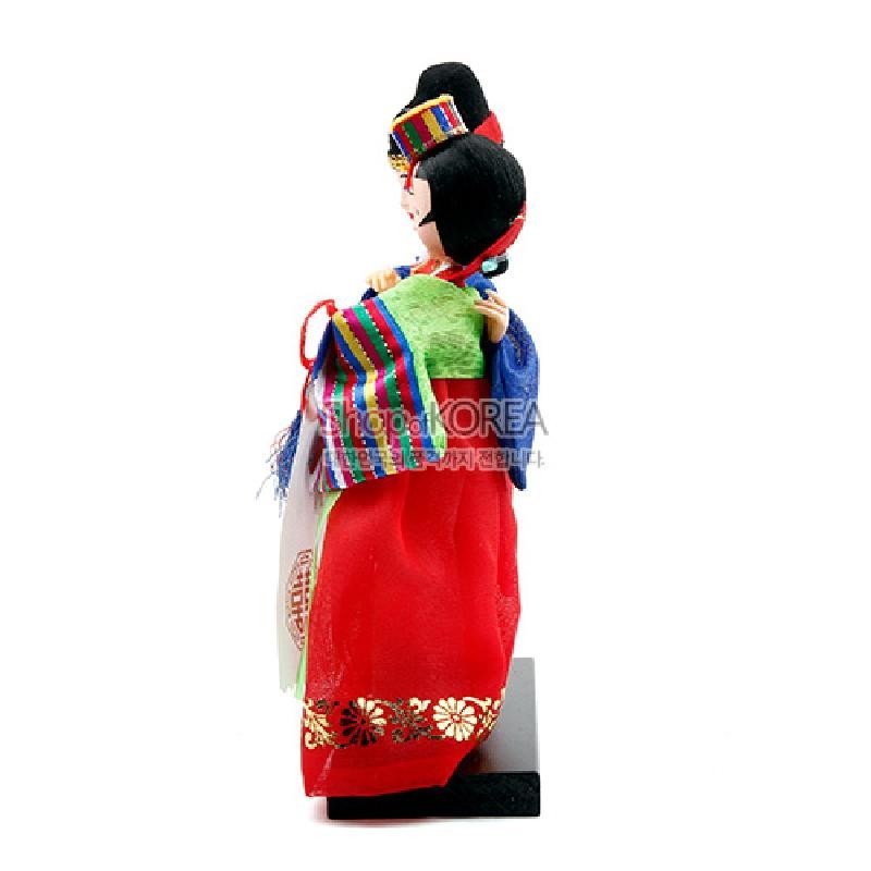 화려한 붉은색 치마와 금빛 꽃문양, 오방색 줄무늬 당의와 비단 장식이 어우러진 전통 혼례 한복 인형 장식.